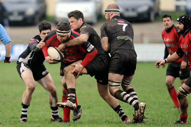 Redruth’s Darren Jacques powers through the tackles of Launceston’s Lewis Webb and Liam Yeo